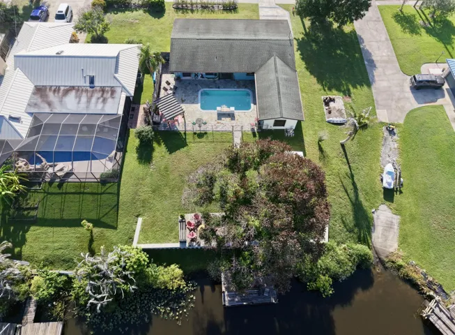 Fenced backyard featuring a paved patio, swimming pool, and a private dock on the waterway