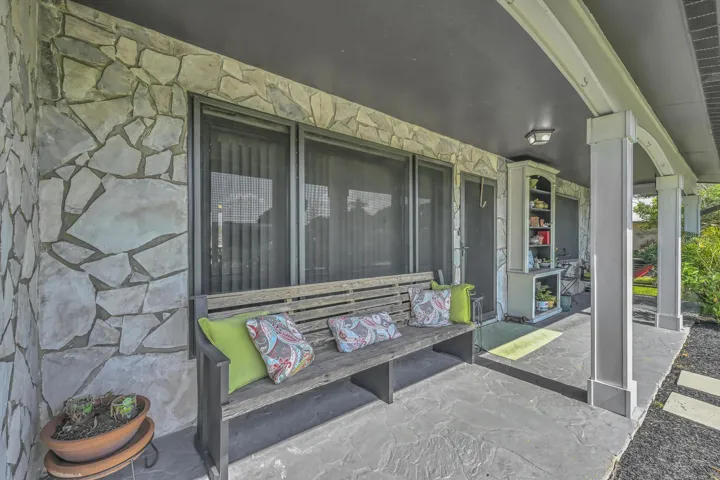 Stone veneer exterior featuring a covered patio with a dark ceiling, recessed lighting, and a built-in shelving unit
