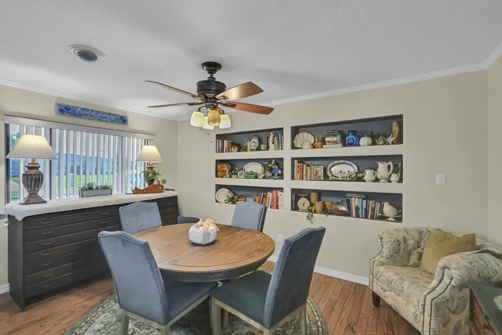 Dining area featuring wood-finish flooring, a ceiling fan with integrated lighting, and crown molding