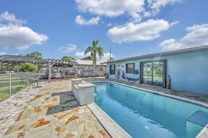 Backyard oasis featuring a swimming pool, flagstone patio, and a wooden pergola structure