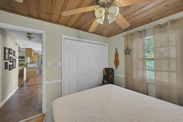 Room featuring a wood-panel ceiling, ceiling fan with integrated lighting, and light neutral wall paint