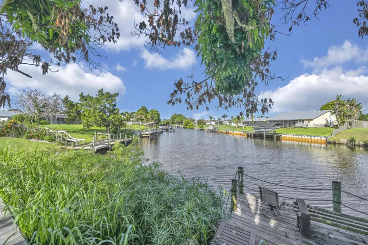 Waterfront property featuring a private wooden dock, lush green lawn, and mature trees