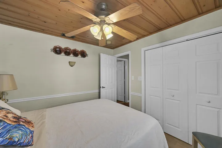 Interior room featuring a wood-panel ceiling, white bi-fold closet doors, and light-colored walls with chair rail molding