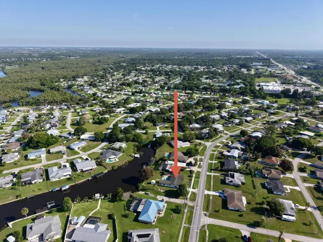 Aerial perspective showcasing a residential neighborhood with a prominent canal system, mature tree canopy, and a clear blue sky