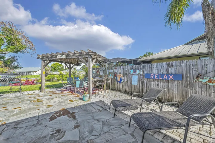 Spacious outdoor patio area featuring flagstone paving, a wooden pergola, and a privacy fence