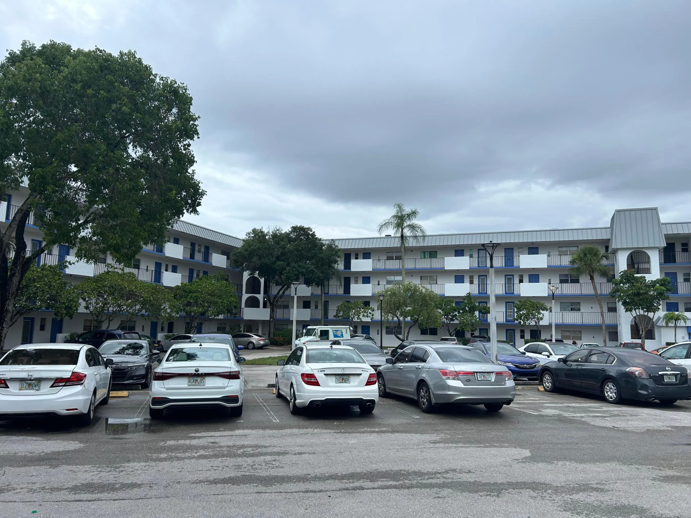 Multi-story residential building featuring white exterior walls with blue accents and dark railings