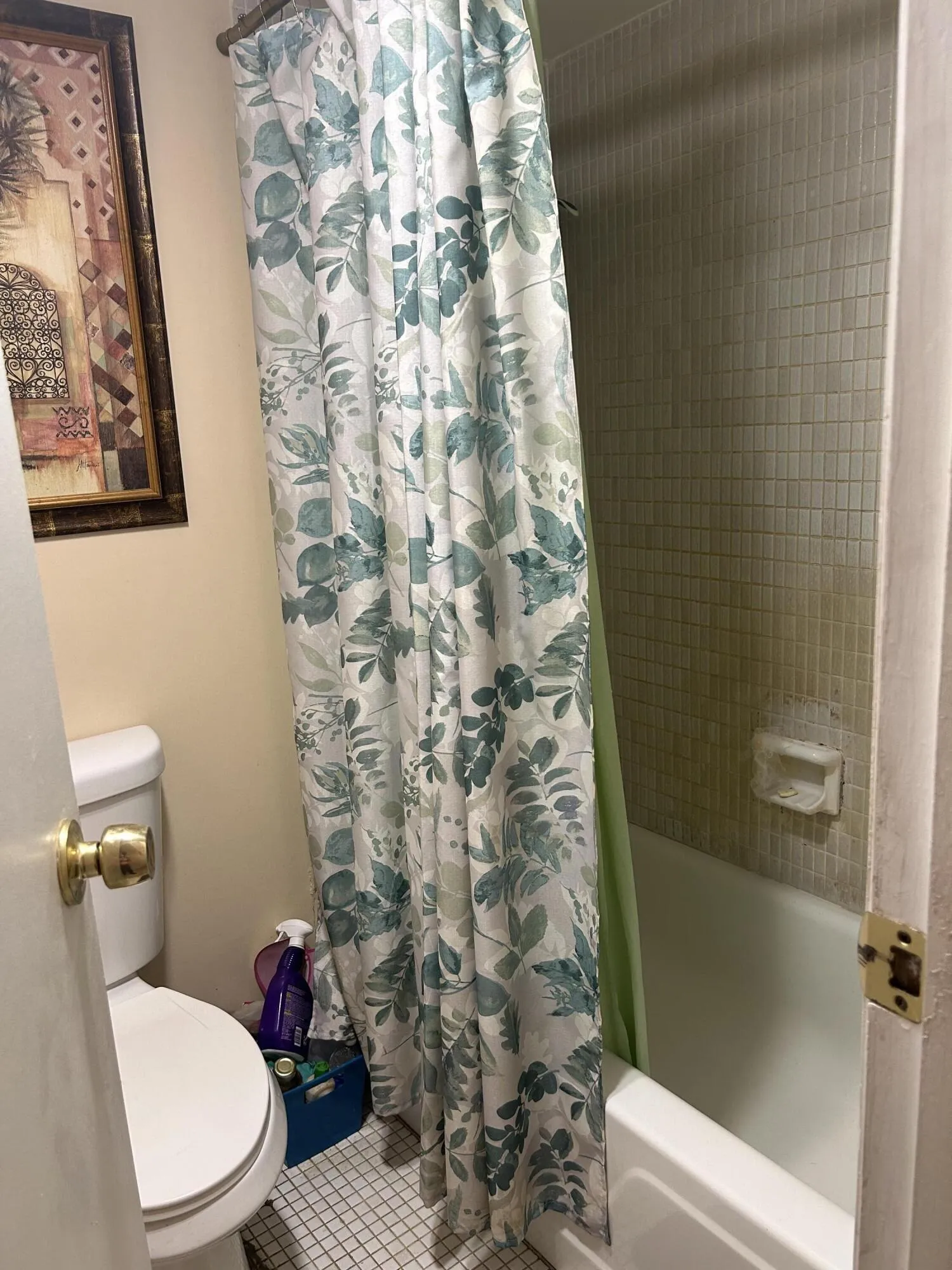 Bathroom featuring a white porcelain toilet, white square floor tiling, and a white bathtub with small rectangular wall tiling