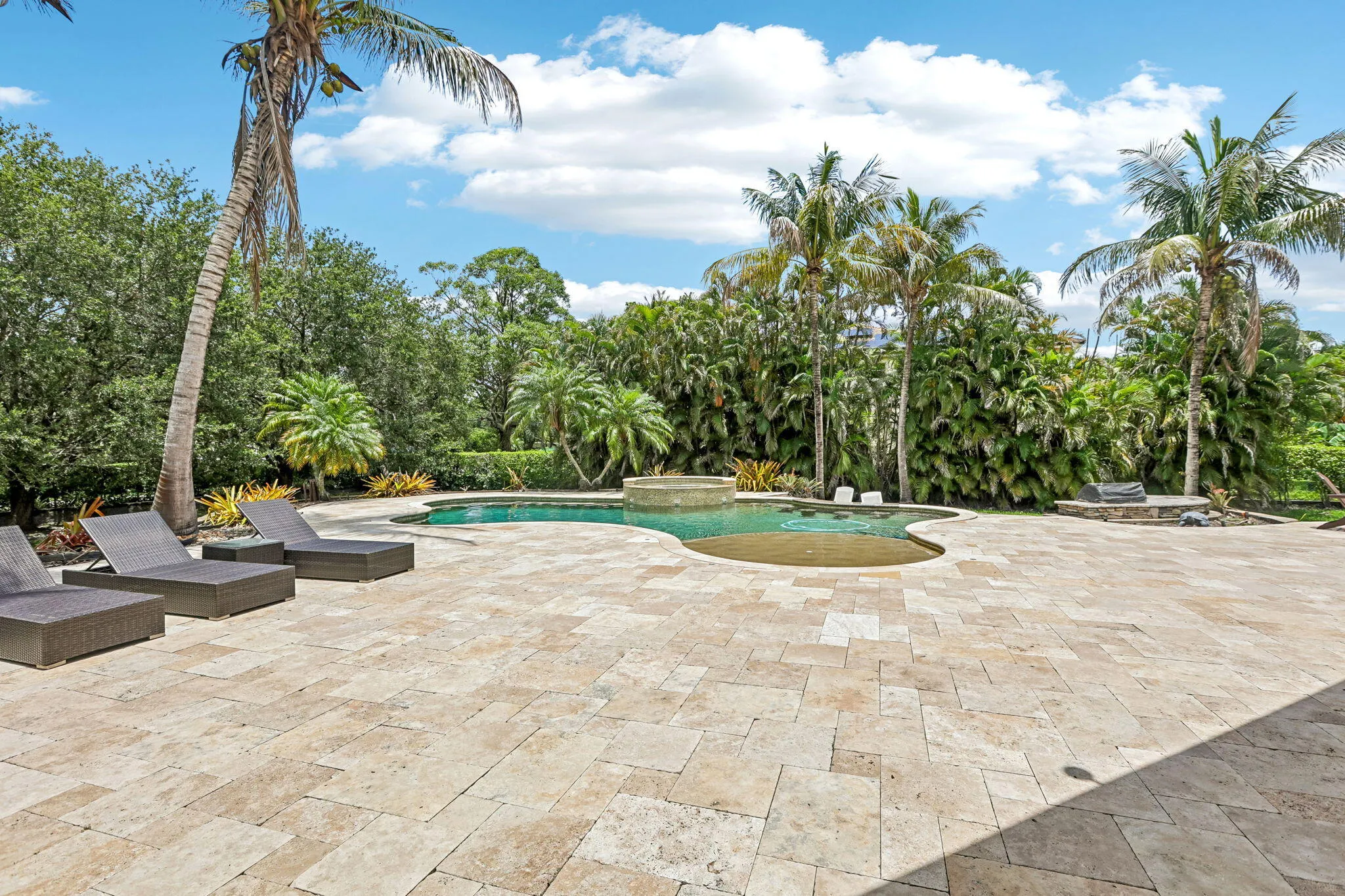 Expansive outdoor living area featuring a freeform swimming pool with an integrated spa