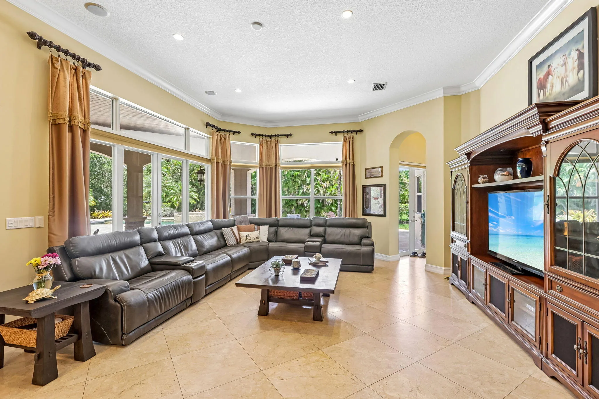 Spacious living area featuring light-toned tile flooring and a bay window wall with transom windows