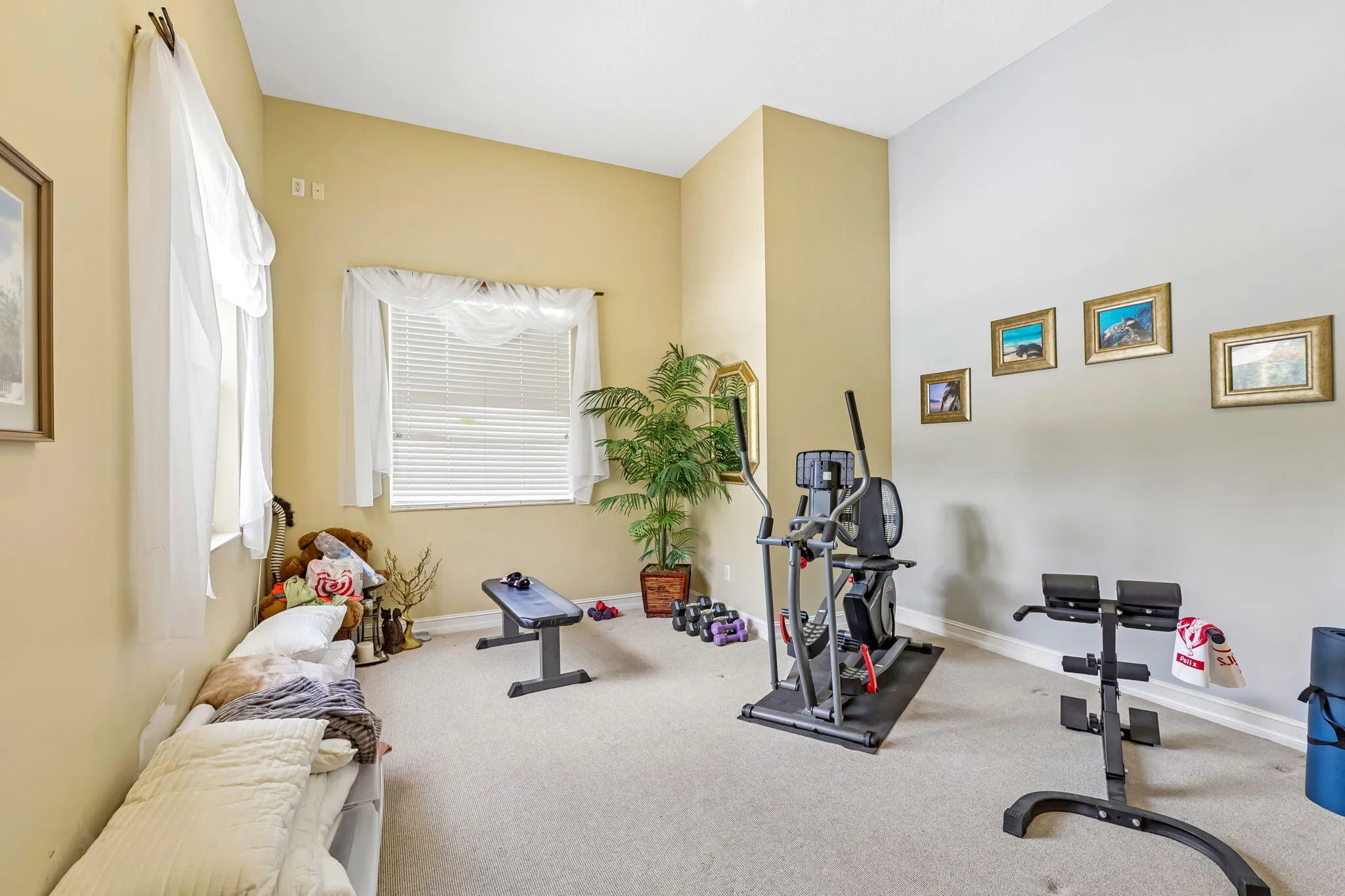 Versatile room featuring two windows with horizontal blinds, carpeted flooring, and a neutral color palette