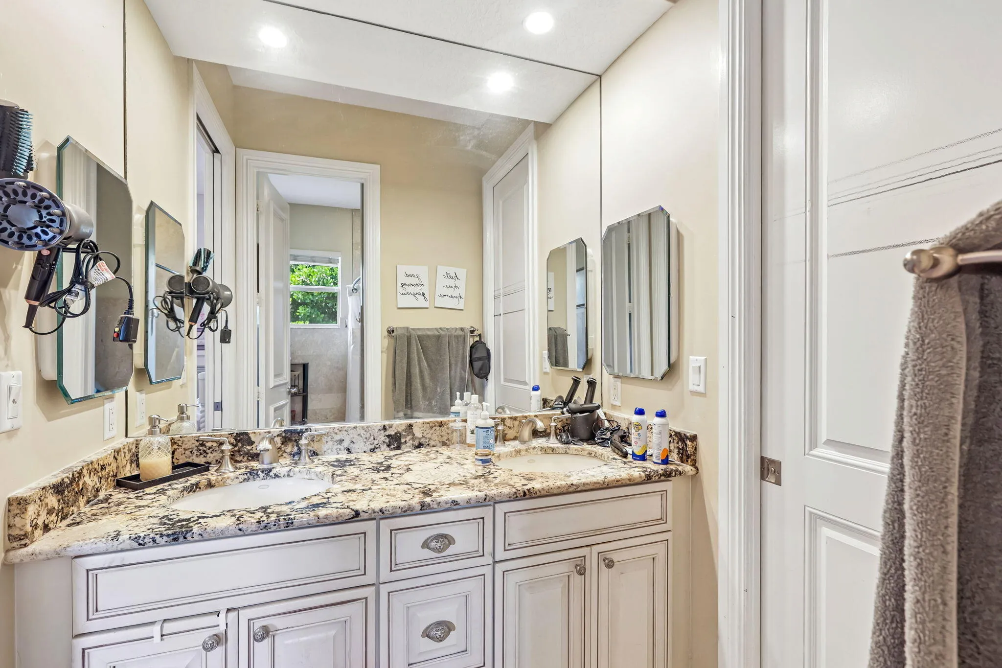 Dual vanity featuring a granite countertop with integrated sinks and white cabinetry