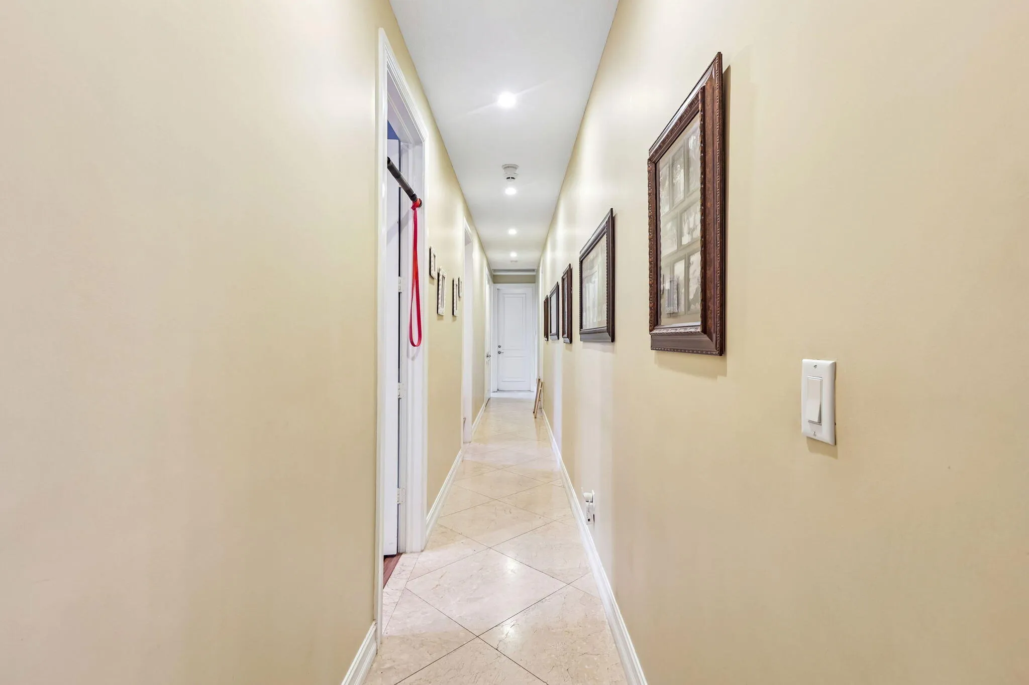 Long hallway featuring recessed lighting and durable tile flooring