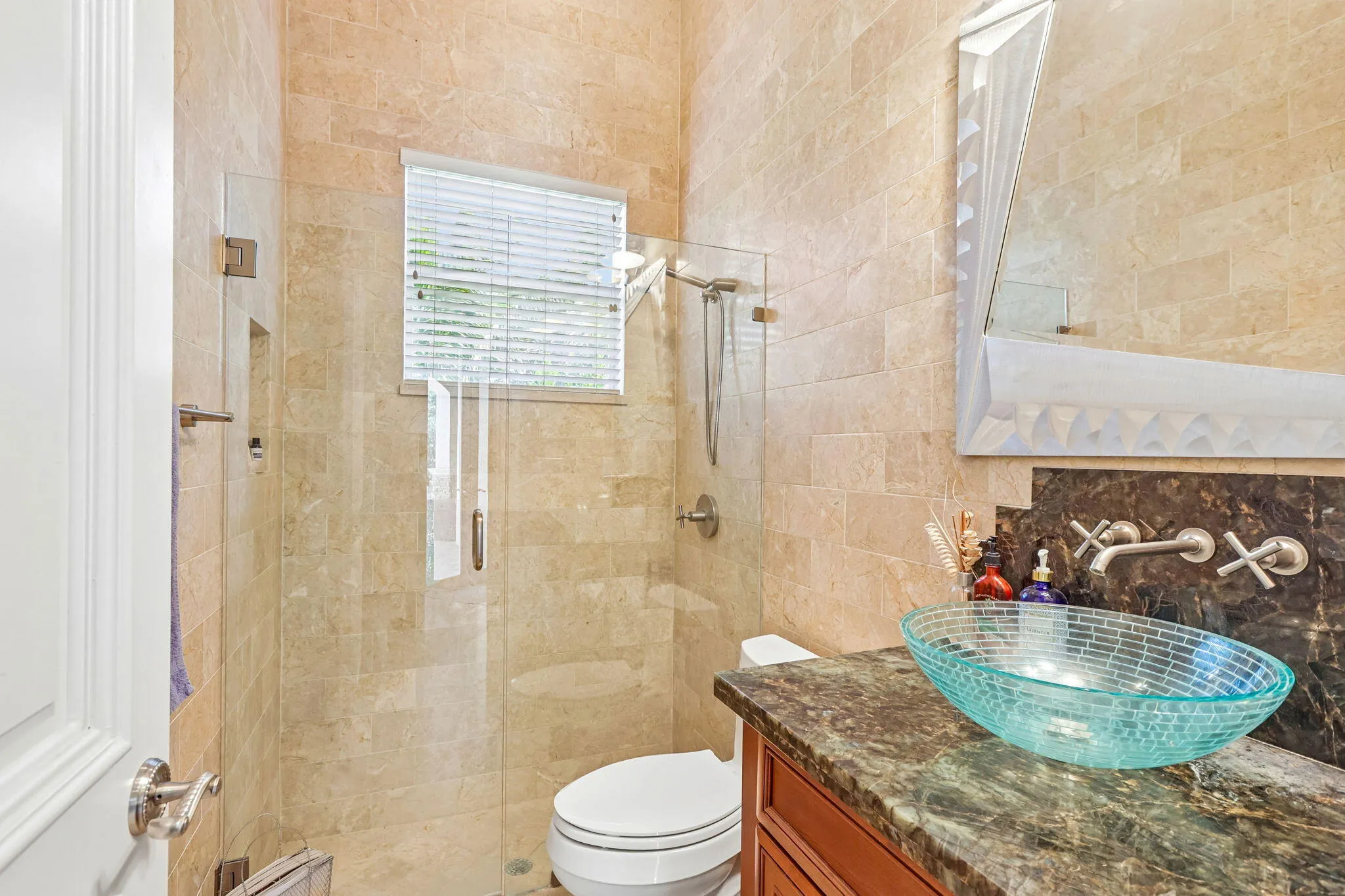 Bathroom featuring a glass vessel sink, stone countertop, and wall-mounted faucet