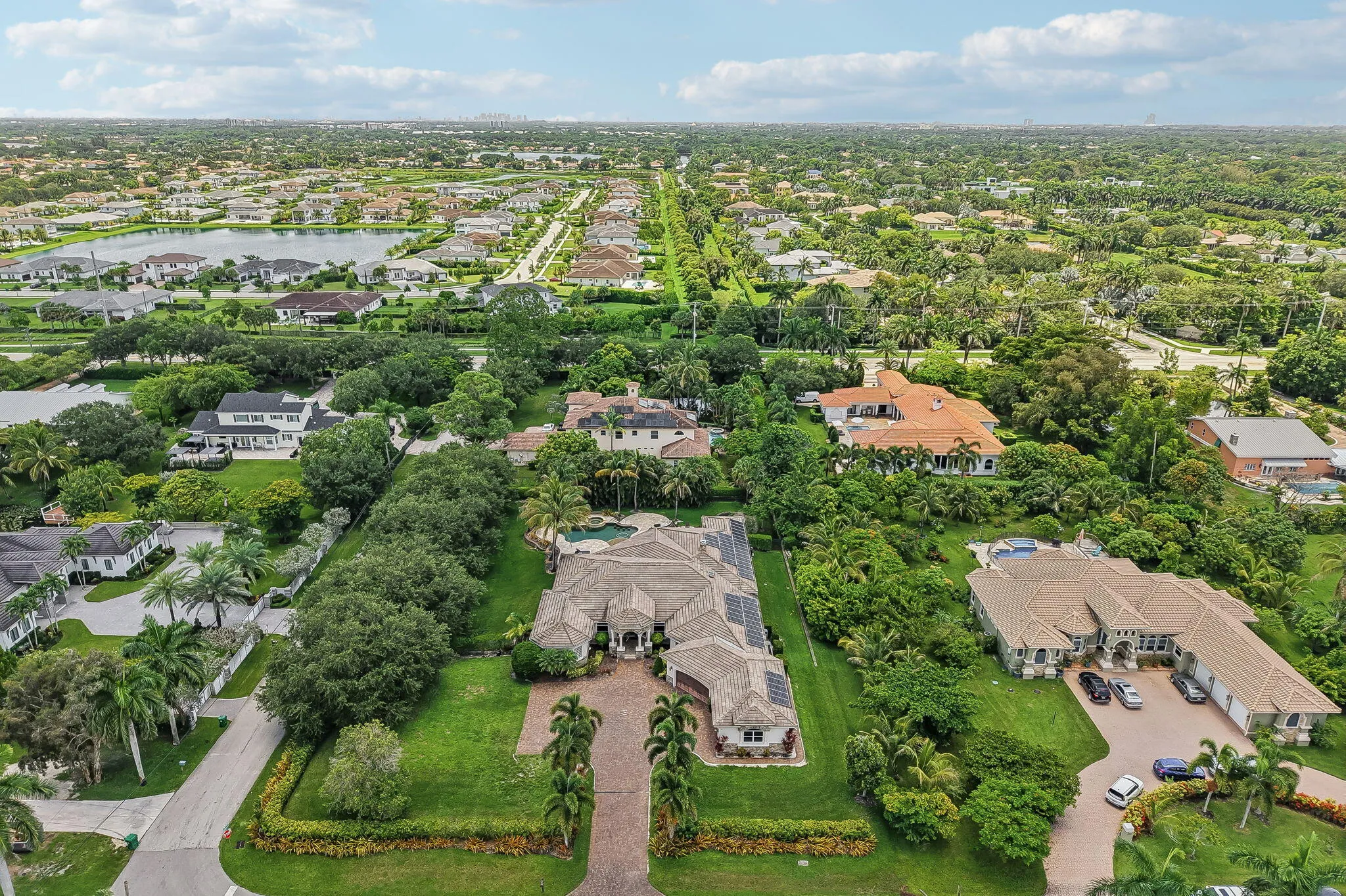 Expansive property featuring a circular driveway, mature tropical landscaping, a private swimming pool, and a tile roof