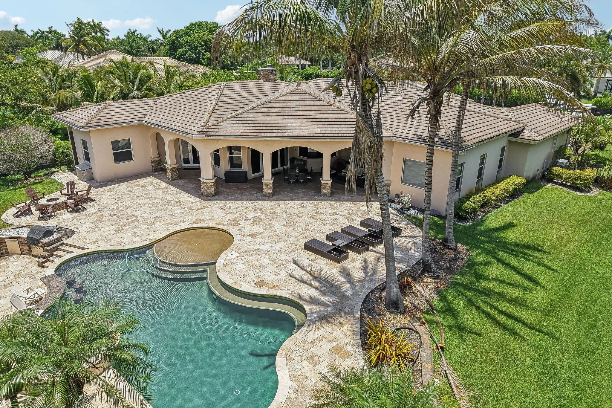 Expansive paver patio featuring a freeform pool with integrated spa and sun shelf