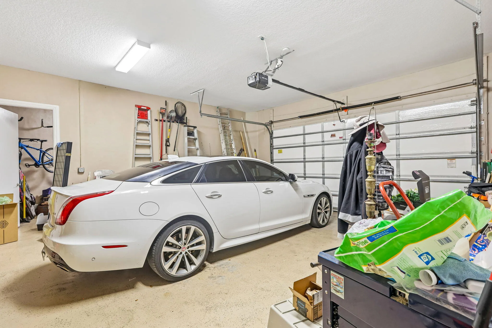 Attached garage featuring a white overhead door, textured ceiling, fluorescent lighting, and a painted concrete floor