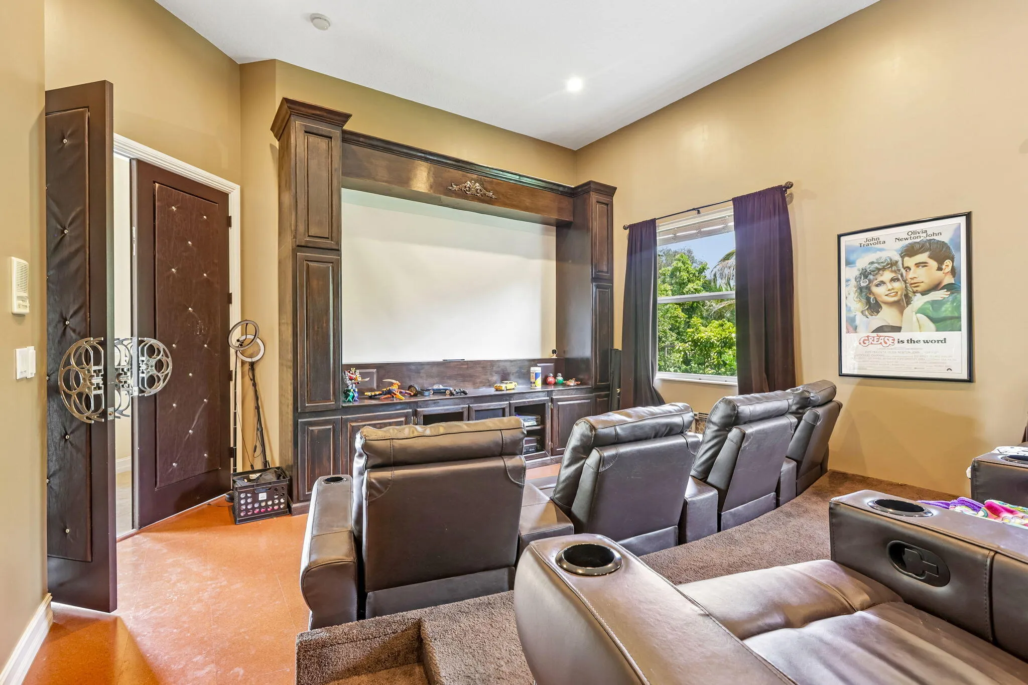 Dedicated media room featuring a built-in entertainment center, a large projection screen, and tiered seating
