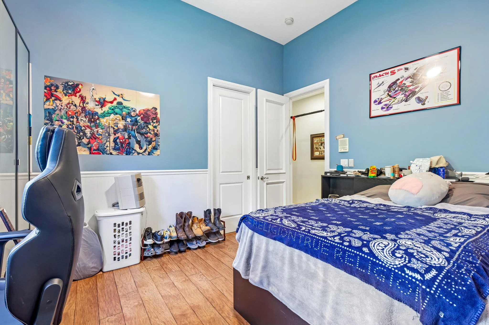 Bedroom featuring blue walls, white wainscoting, and wood-finish flooring