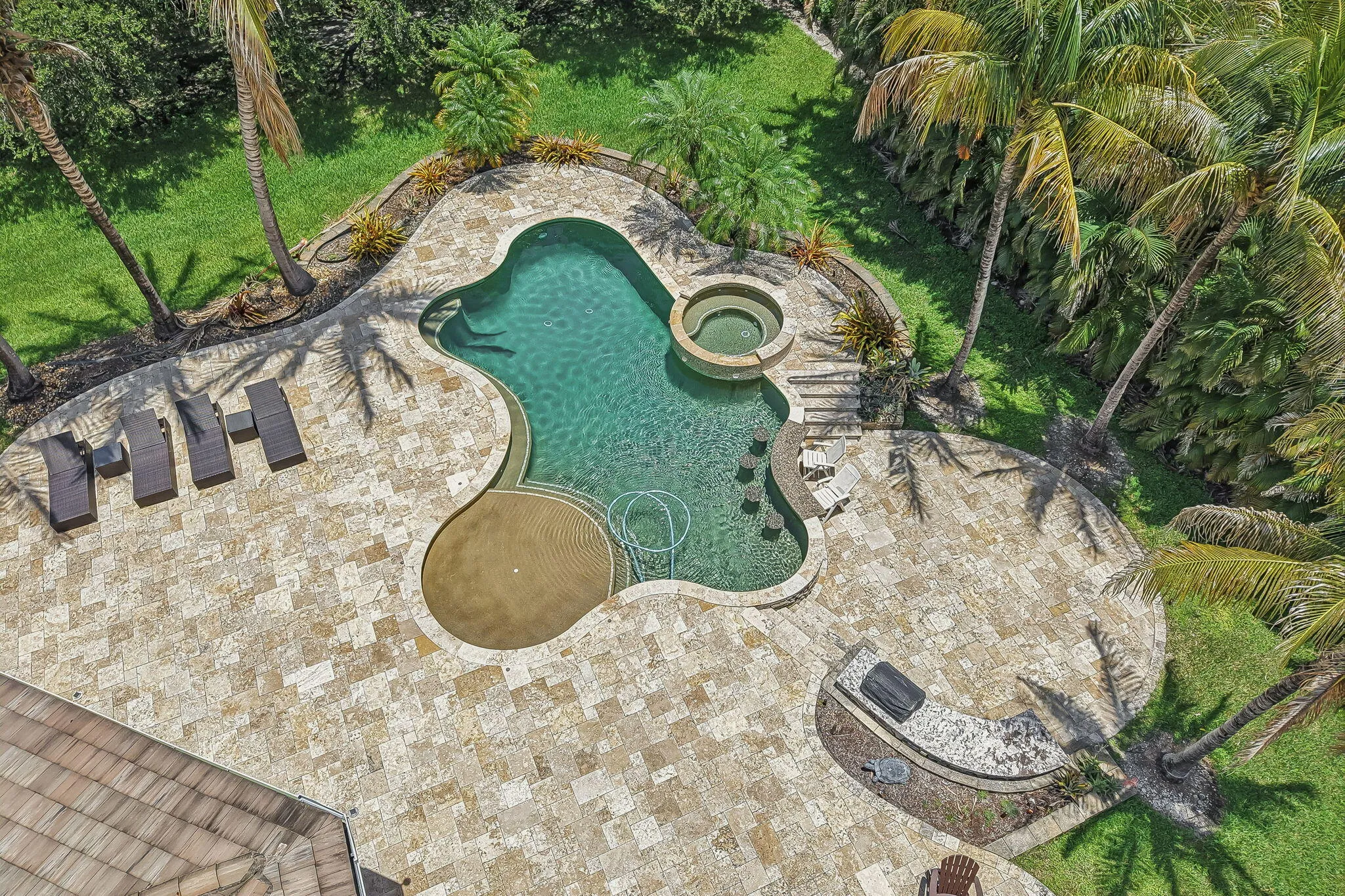 Freeform swimming pool with an integrated spa, surrounded by extensive paver decking