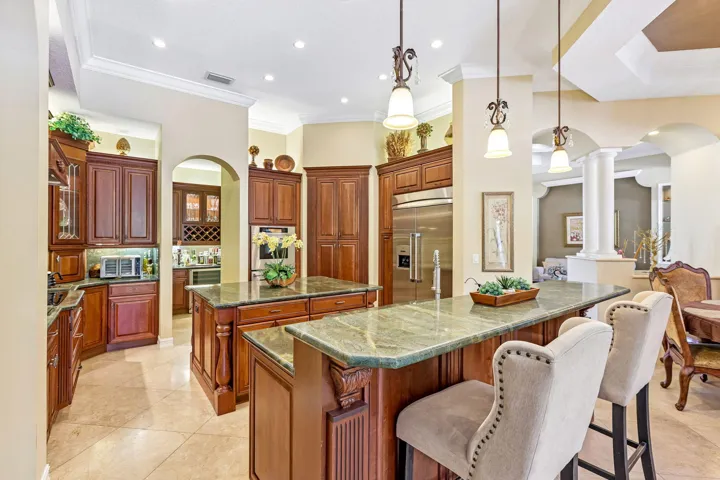 Kitchen featuring dual islands with green stone countertops, extensive wood cabinetry, stainless steel appliances, and recessed lighting