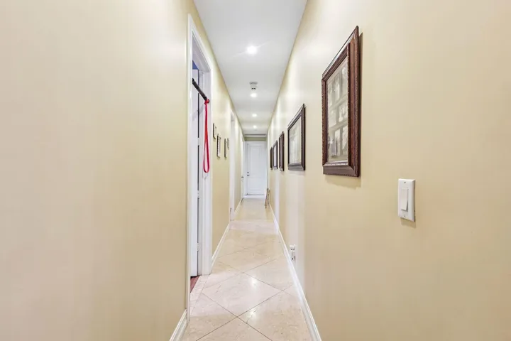 Long hallway featuring recessed lighting and durable tile flooring
