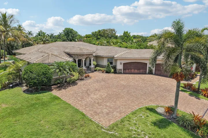 Mediterranean-style residence featuring a tile roof, extensive paver driveway, and a three-car garage