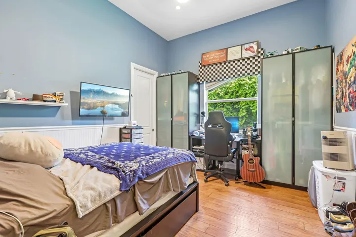 Room featuring wood-finish flooring, a double-hung window, and wainscoting