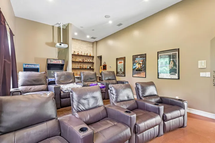 Dedicated media room featuring tiered seating, individual leather recliners with cup holders, a built-in projector, and recessed ceiling lighting