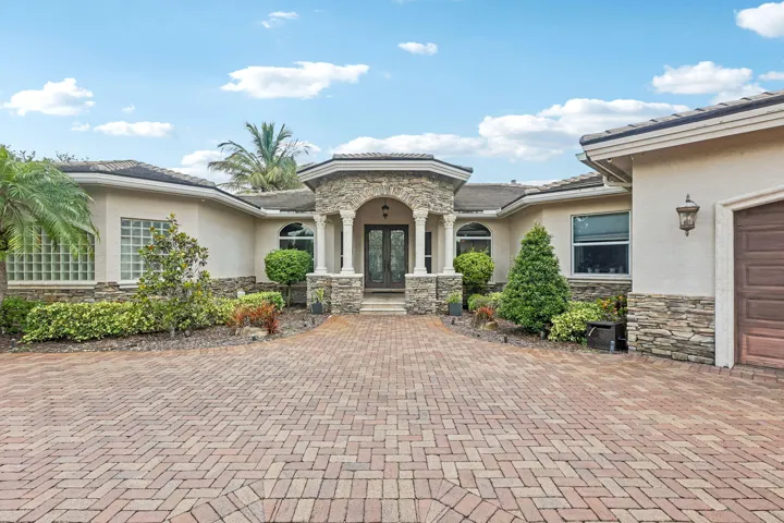 Stucco exterior with stone veneer accents and a tiled roof