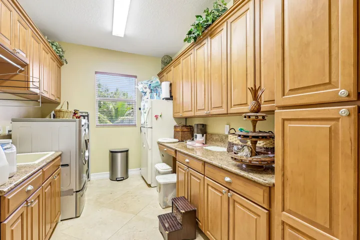 Utility room featuring extensive wood-finish cabinetry, light-toned countertop, and recessed lighting