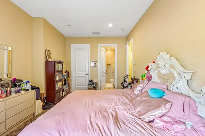 Recessed lighting illuminates the room, featuring a doorway leading to a tiled bathroom