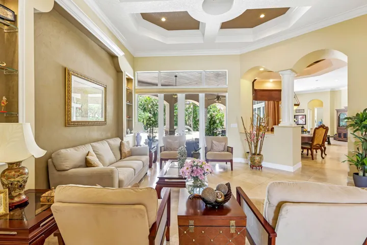 Spacious living area featuring coffered ceilings, built-in display shelving, and glass sliding doors