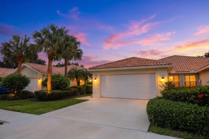 Mediterranean-style architecture with a tile roof, an integrated garage, a concrete driveway, and mature palm trees
