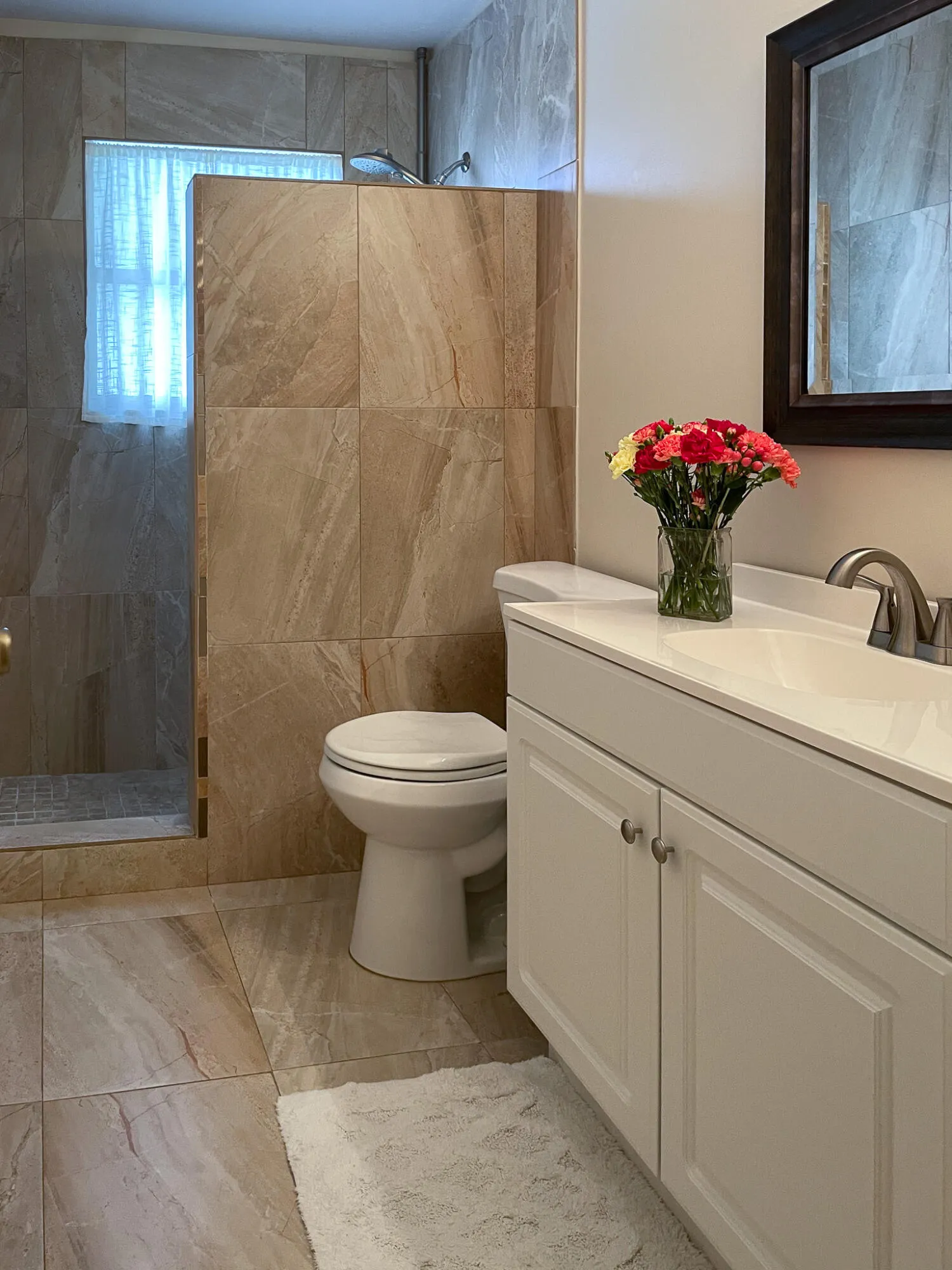 Walk-in shower with natural stone-look tile surround and glass partition