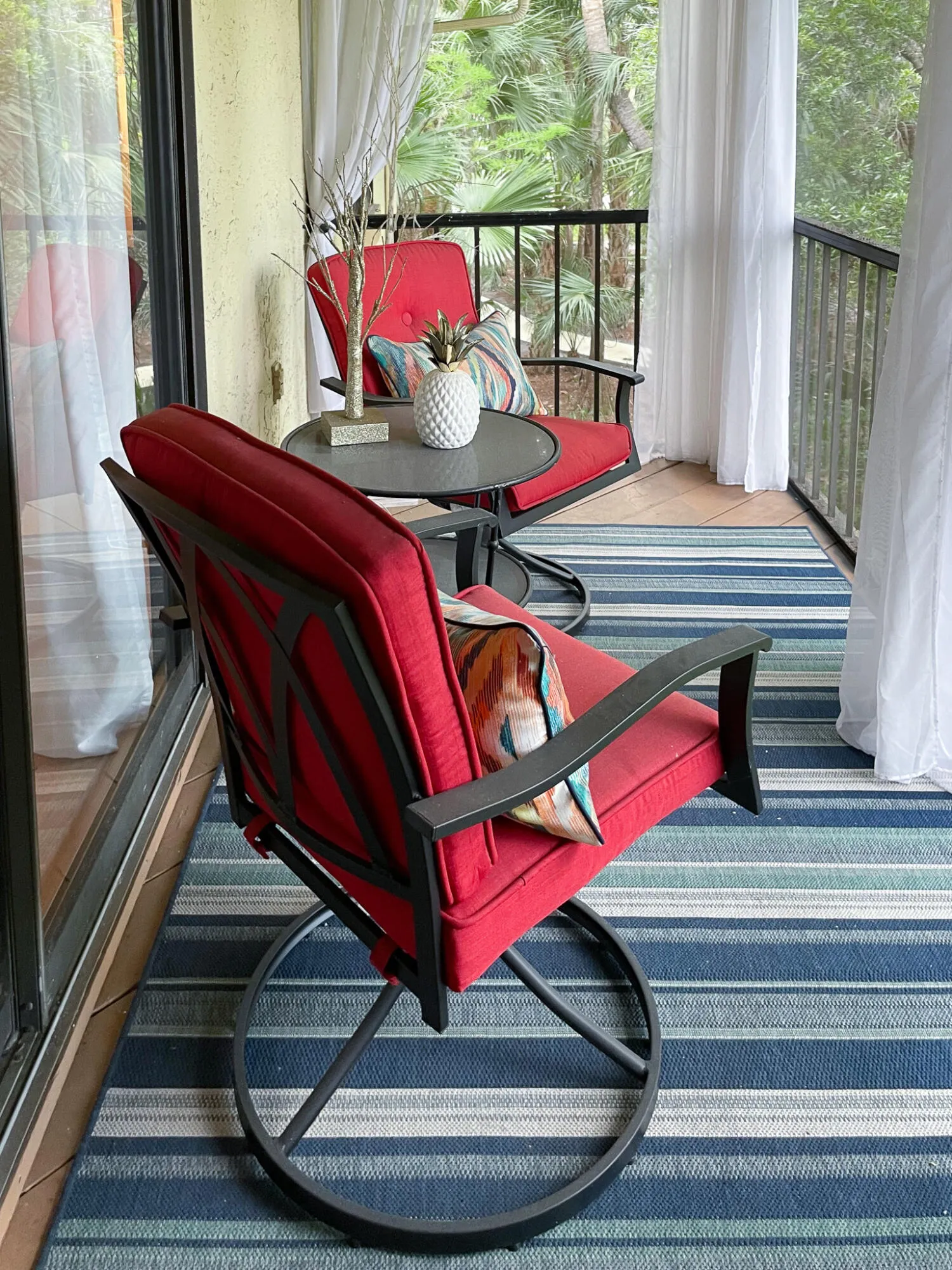 Private balcony space featuring a striped area rug and black metal railings