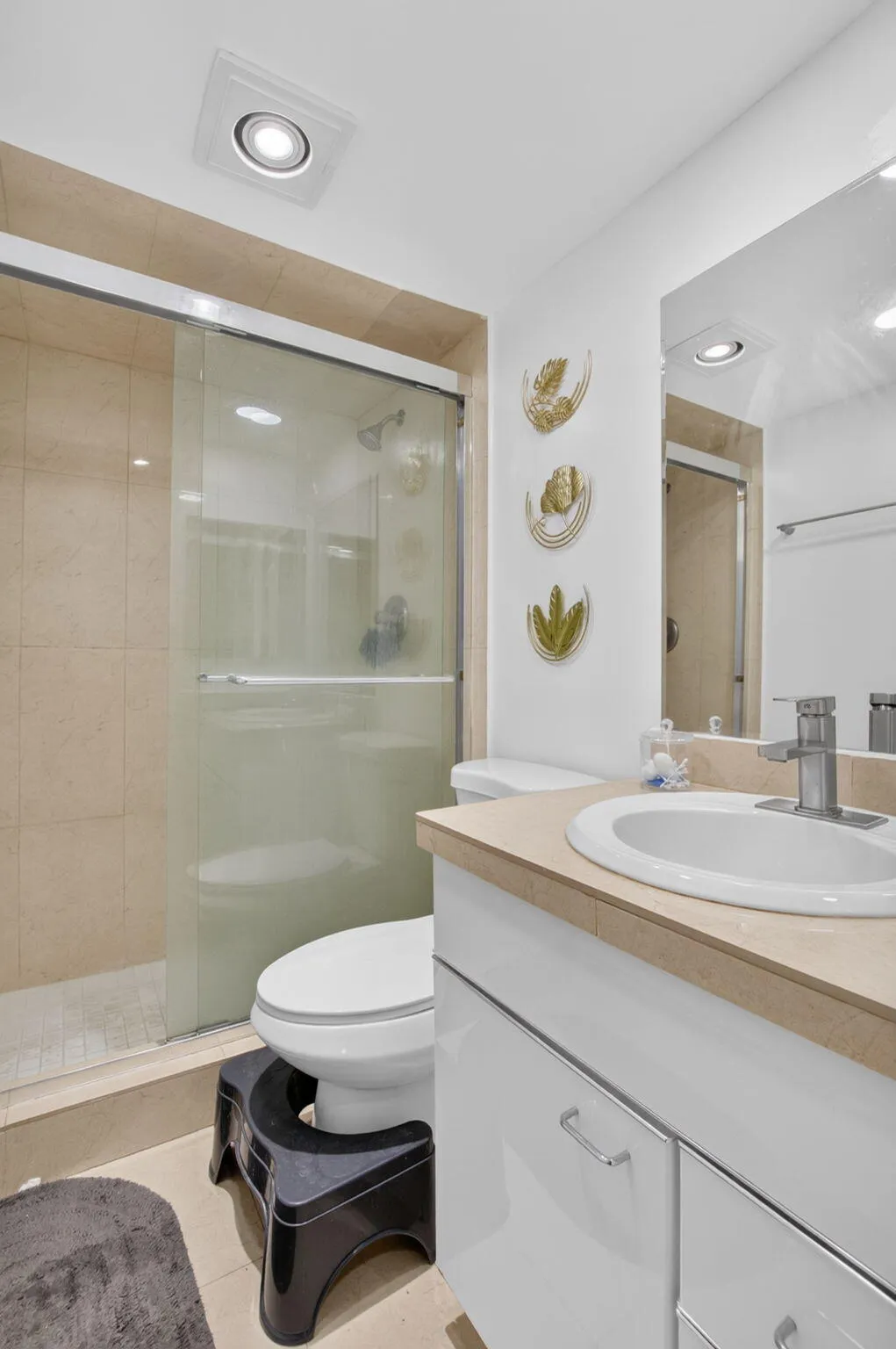 Contemporary bathroom featuring a spacious shower with glass enclosure, beige tile surround, and built-in lighting