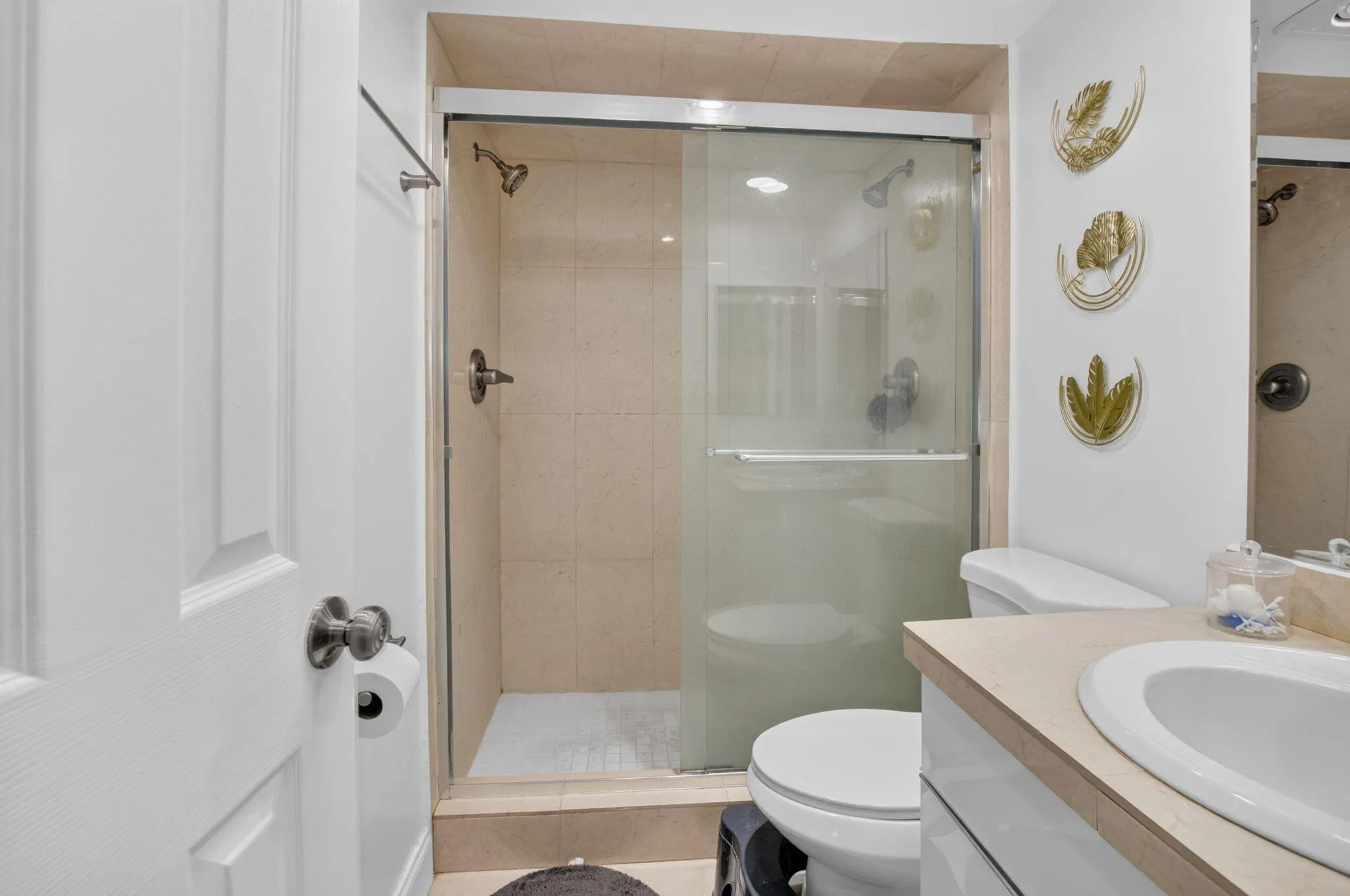 Bathroom featuring a glass-enclosed shower with tile surround, a single vanity with an integrated sink and light-toned countertop, and a white toilet