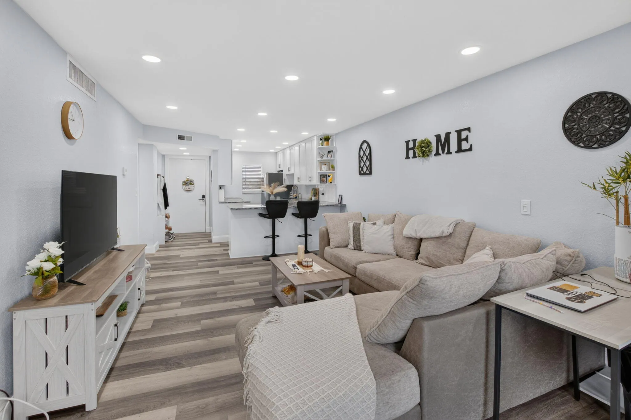 Open-concept living area featuring Vinyl wood-finish flooring, recessed lighting, and a breakfast bar with countertop seating
