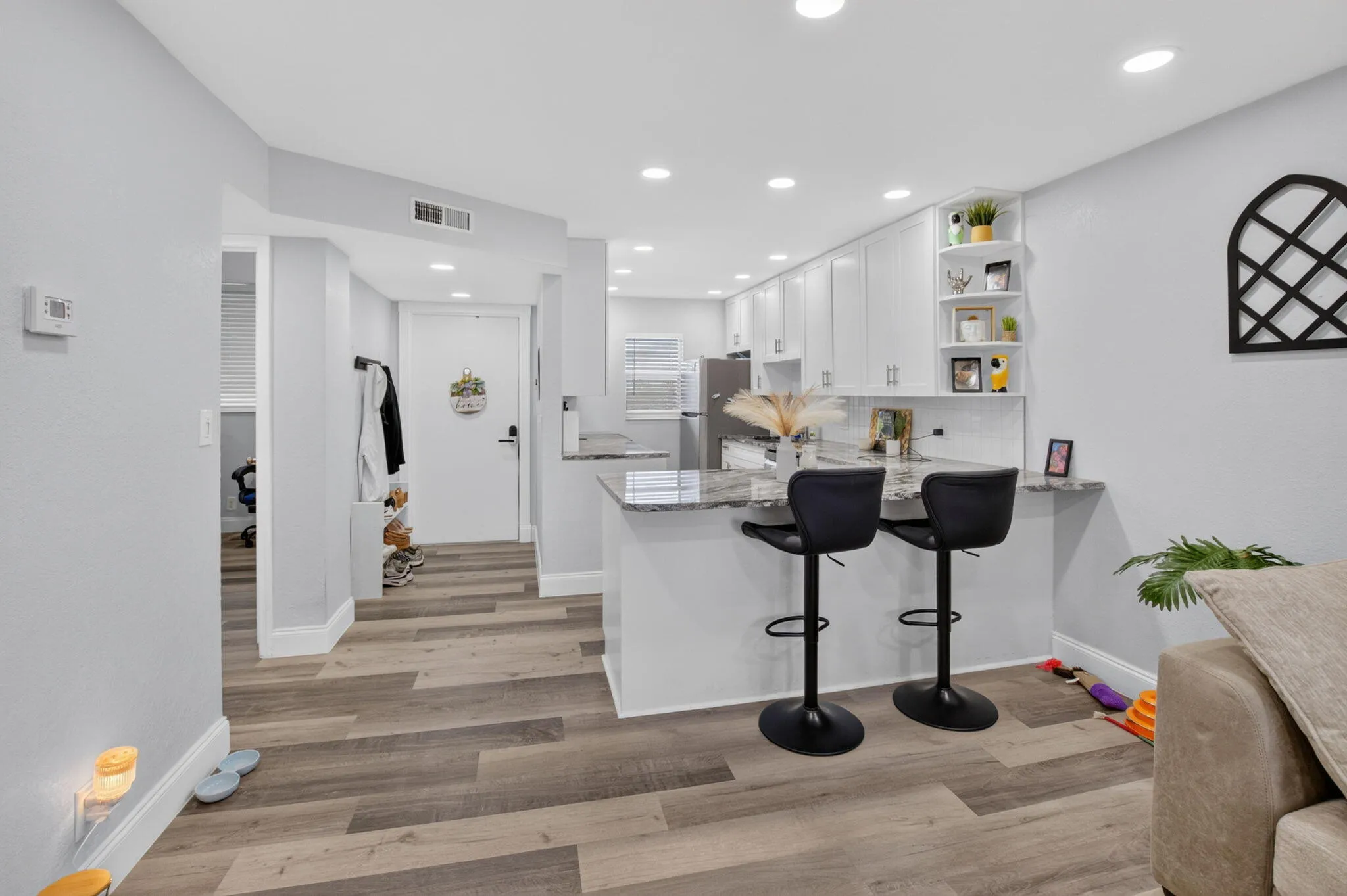 Modern kitchen featuring white shaker cabinetry, stainless steel appliances, a breakfast bar with stone countertops, and recessed lighting