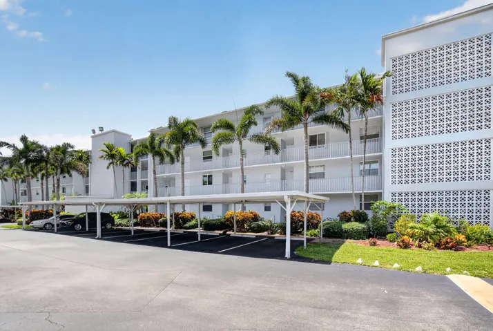 Multi-story condominium building featuring gray exterior, private balconies, and covered parking