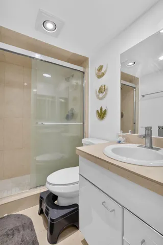 Contemporary bathroom featuring a spacious shower with glass enclosure, beige tile surround, and built-in lighting