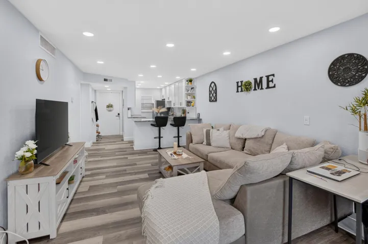 Open-concept living area featuring Vinyl wood-finish flooring, recessed lighting, and a breakfast bar with countertop seating