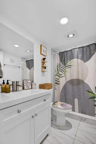 Bathroom featuring a white vanity with integrated sink, chrome faucet, and white shaker-style cabinetry