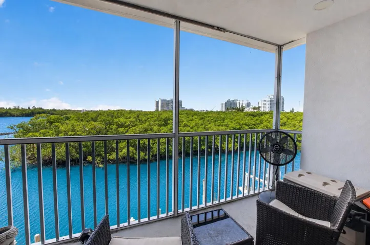 Expansive screened balcony featuring a water backdrop and distant green foliage
