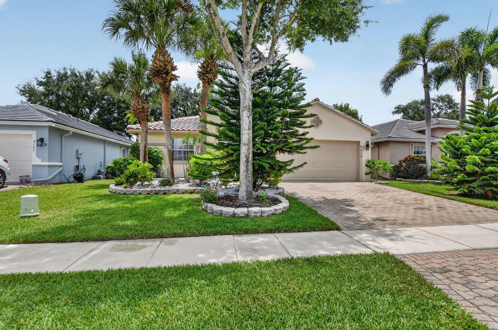 Neutral-toned residence featuring a paver driveway, an integrated garage, and a tiled roof