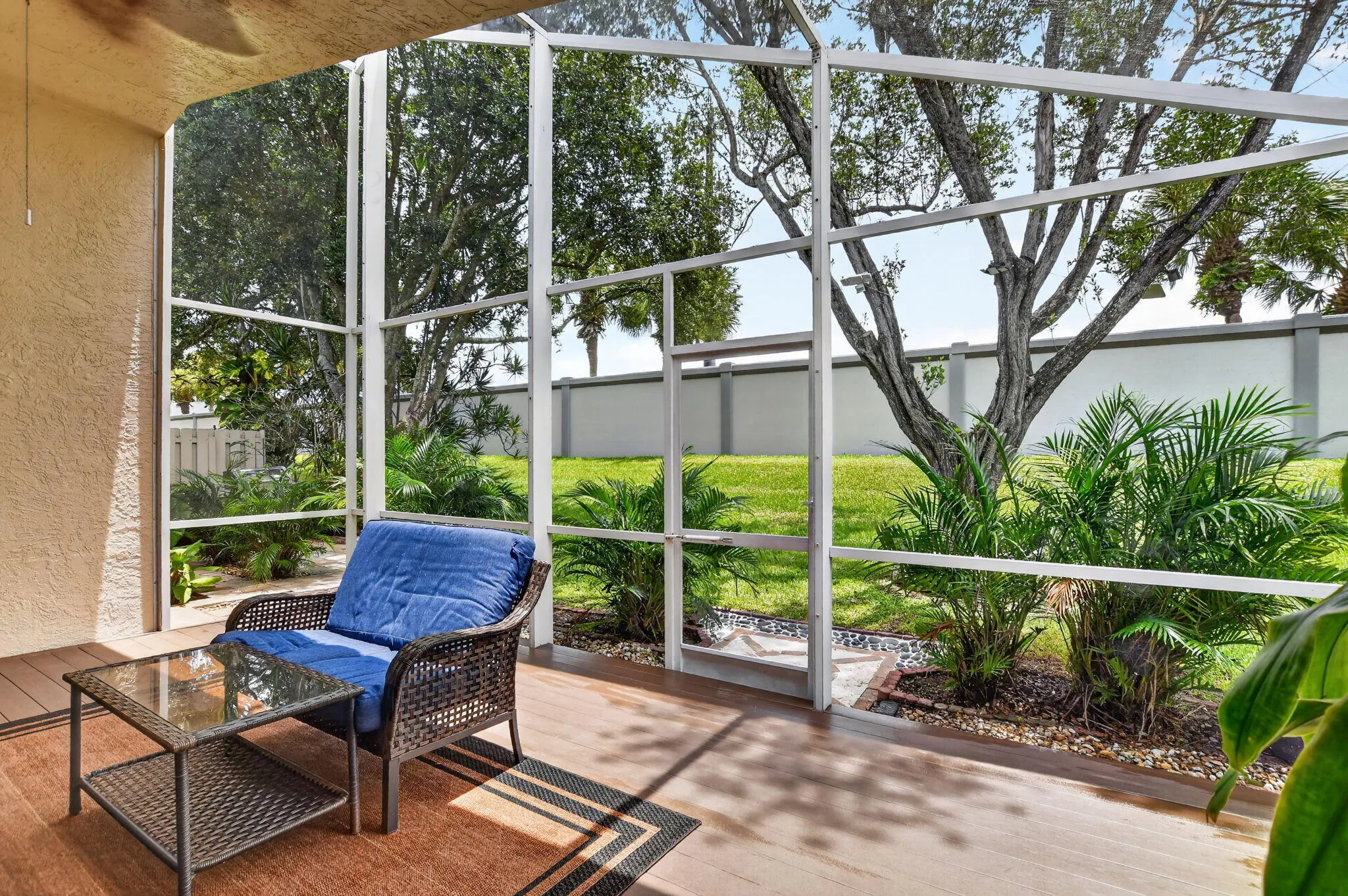 Screened patio featuring wood-finish flooring, stucco exterior wall, and a ceiling fan