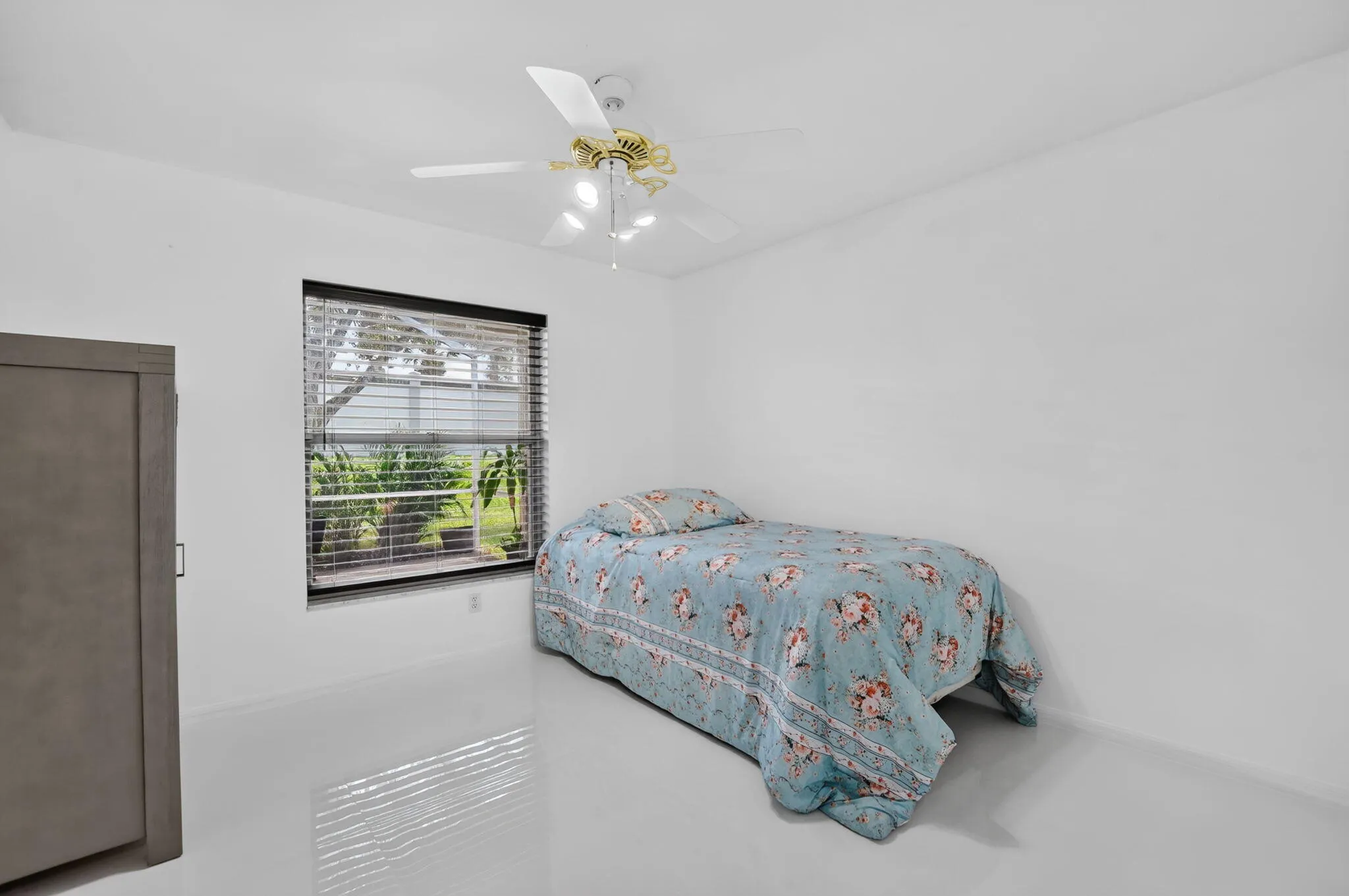 Bright interior space featuring a window with horizontal blinds, a ceiling fan with integrated lighting, and light-toned flooring