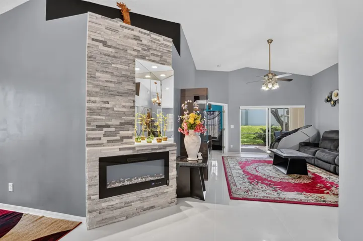 Living space featuring an electric fireplace with stacked stone surround, vaulted ceiling, and sliding glass doors