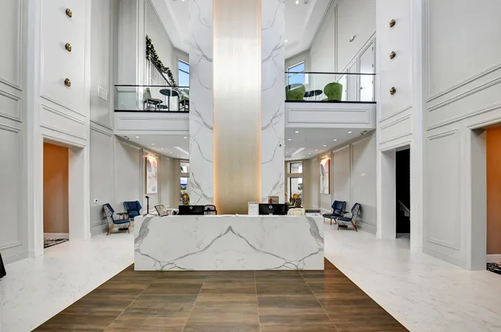Grand foyer featuring a two-story ceiling and a central column with marble-finish paneling