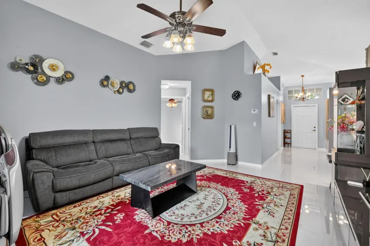 Spacious living area featuring vaulted ceilings, sleek tile flooring, a contemporary ceiling fan, and ample wall space